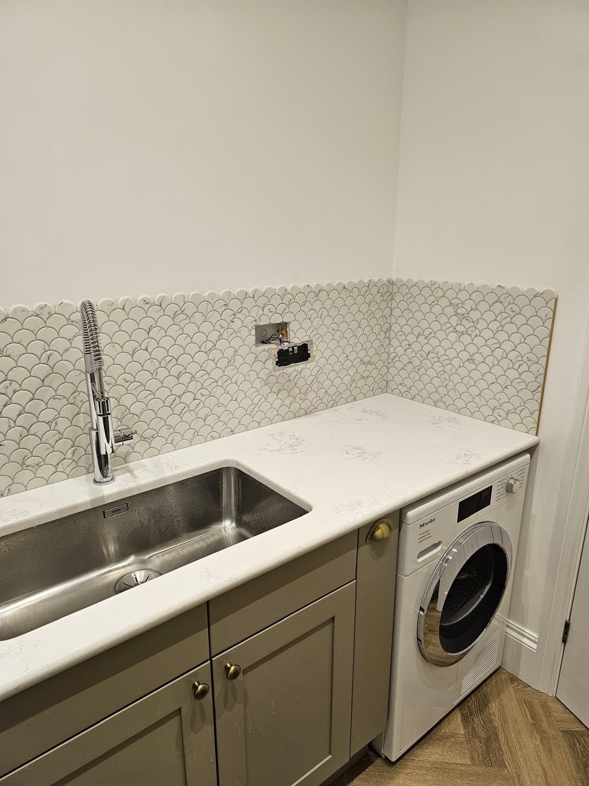 Finished utility room fitted by SINA Kitchen Fitters: green shaker units, white worktop, undermount sink and washing machine
